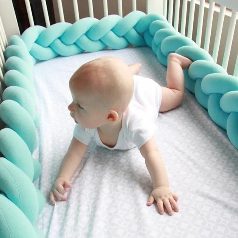 Bébé allongé dans son berceau entouré d'une tresse de lit bleu