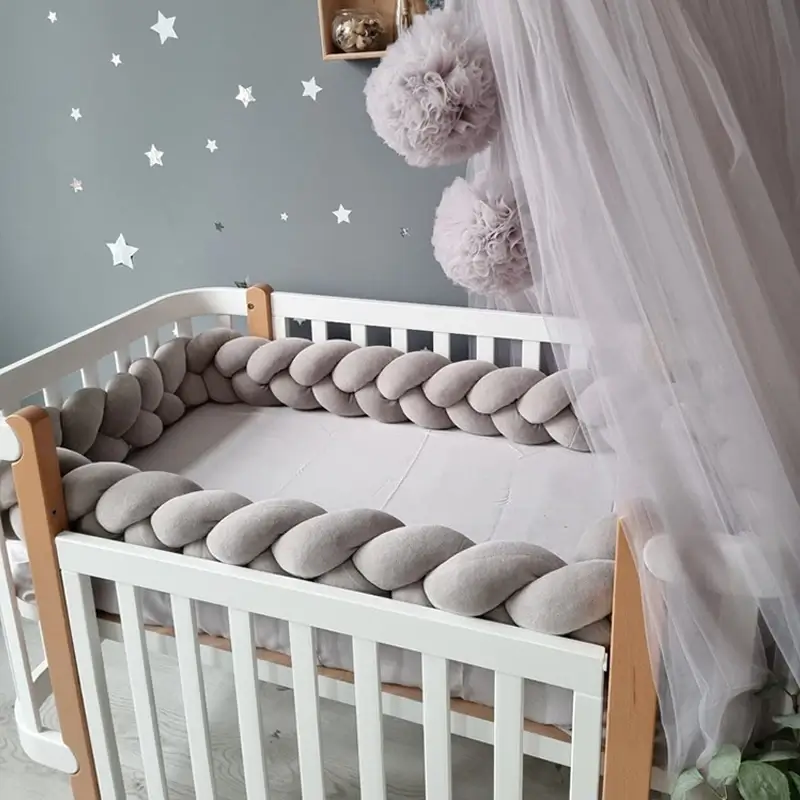 Tour de lit tressé gris autour d'un berceau bébé