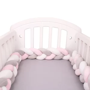 Tour de lit tressé rose gris blanc dans un lit bébé